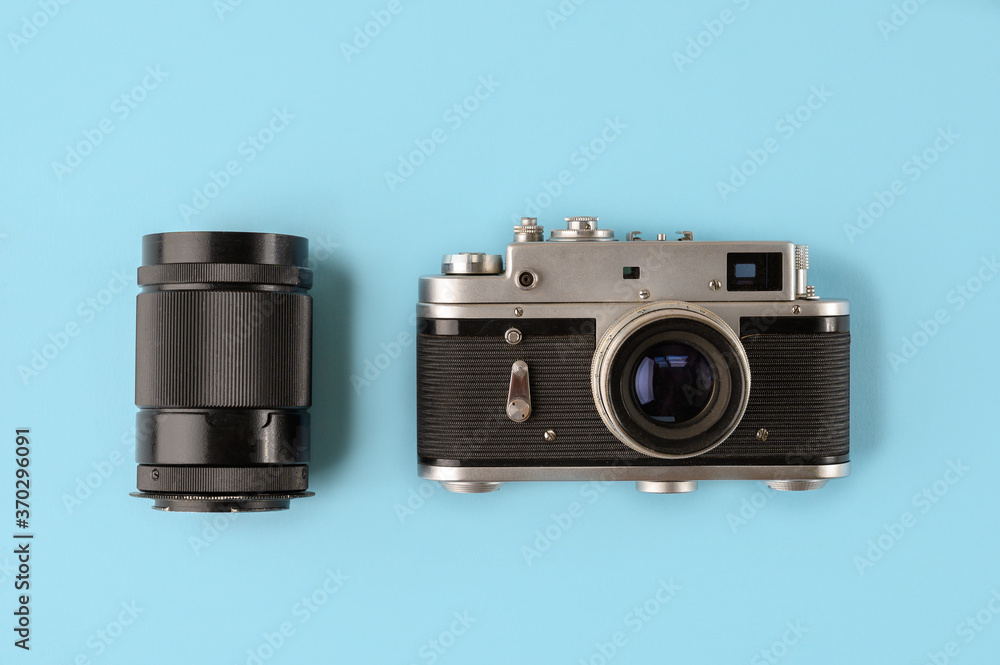 Retro photo camera with lens on blue background, top view