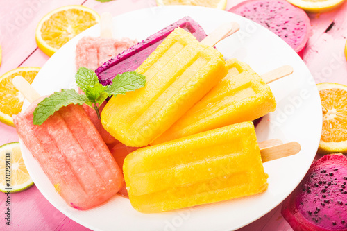 Various fresh fruit popsicles placed on wooden board background
