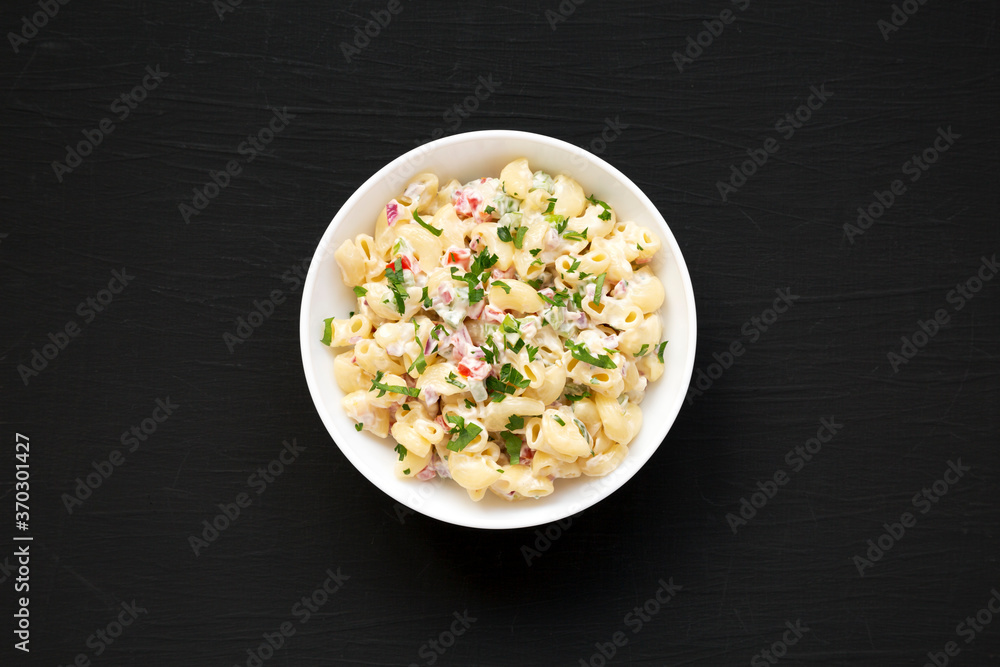 Homemade Macaroni Salad in a white bowl on a black background, top view. Flat lay, overhead, from above. Homemade Macaroni Salad in a white bowl on a black background, top view. Flat lay, overhead, from above.