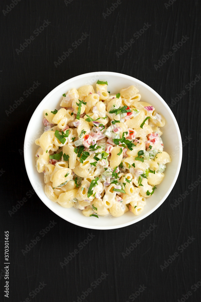 Homemade Macaroni Salad in a white bowl on a black background, top view. Flat lay, overhead, from above. Homemade Macaroni Salad in a white bowl on a black background, top view. Flat lay, overhead, from above.