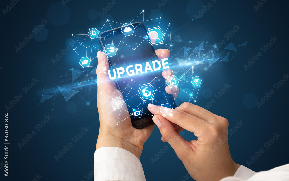 Female hand holding smartphone with UPGRADE inscription, modern technology concept Female hand holding smartphone with UPGRADE inscription, modern technology concept