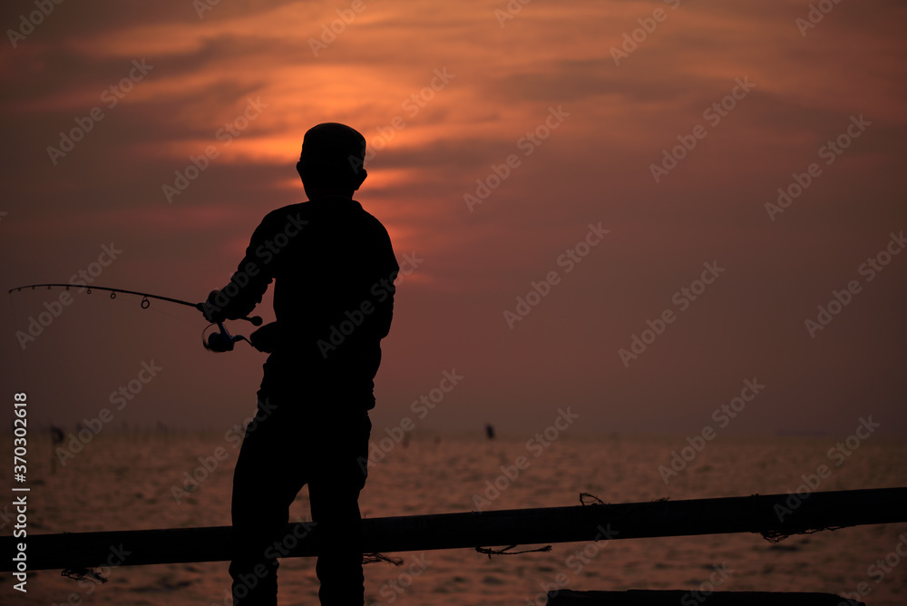 The fisherman silhouette with sunset sky