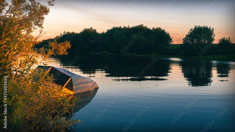 Fototapeta premium River view with sunken fishing boat at sunrise
