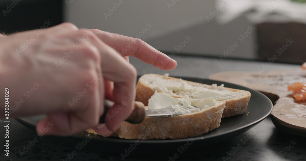 man spread cream cheese on ciabatta slice on black plate man spread cream cheese on ciabatta slice on black plate