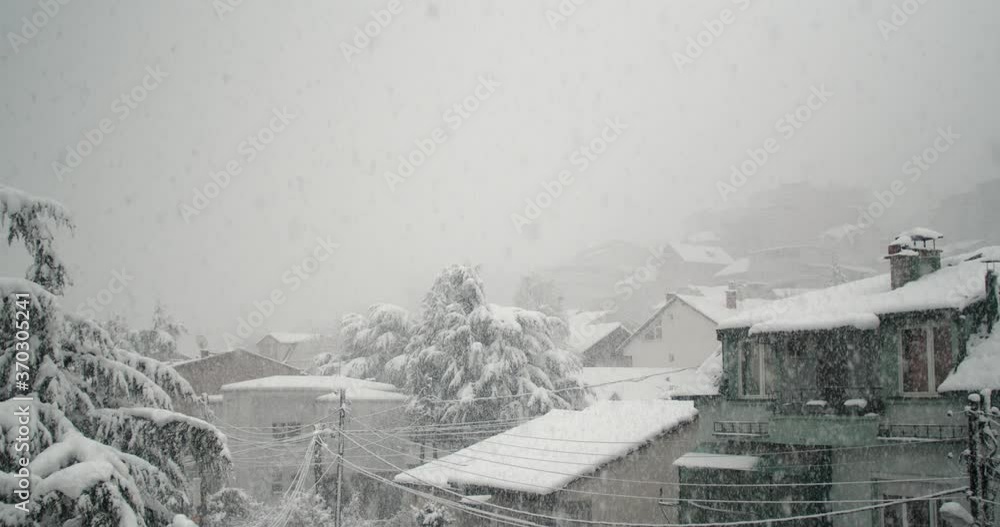 Heavy snow falling in the city with small houses Heavy snow falling in the city with small houses