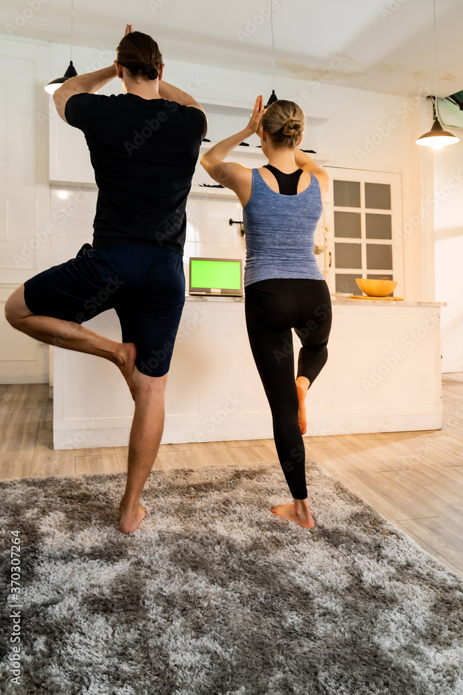 Obraz premium White caucasian couple do tree pose yoga at home