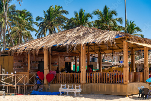 Tropical beach cafe bar hut with palm trees at background
