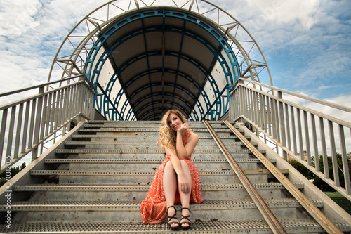 Beautiful lady in long red dress sitting on the stairs 
