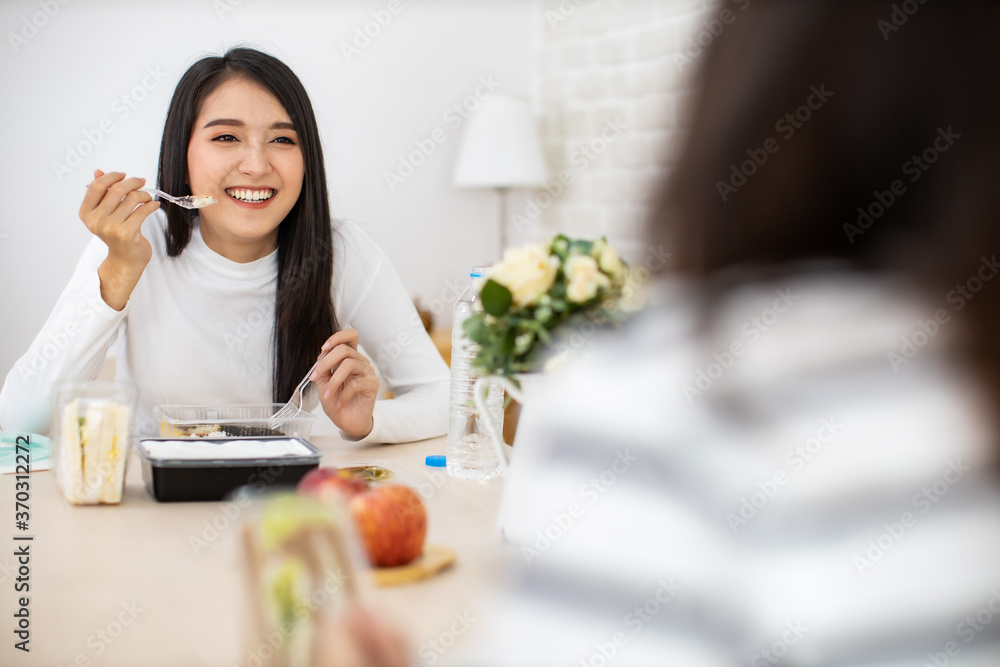 Young Asian woman sitting separated in restaurant or home eating food with table protect infection from coronavirus covid-19, new normal restaurant and social distancing concept. Young Asian woman sitting separated in restaurant or home eating food with table protect infection from coronavirus covid-19, new normal restaurant and social distancing concept.