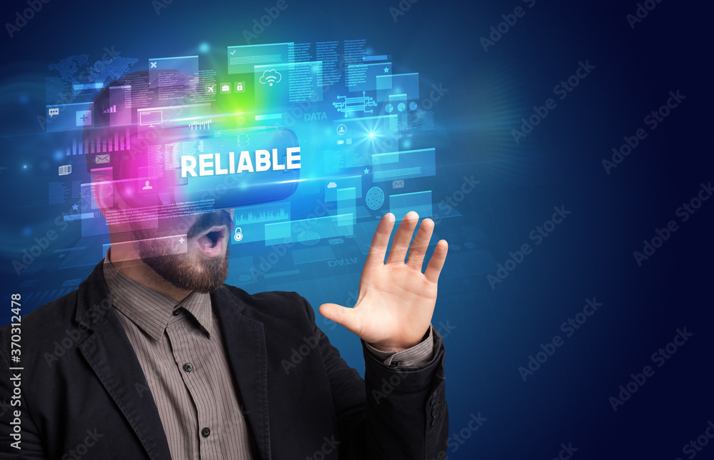 Businessman looking through Virtual Reality glasses with RELIABLE inscription, innovative security concept Businessman looking through Virtual Reality glasses with RELIABLE inscription, innovative security concept