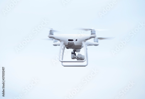 Quadcopter with camera aboard flying in sky