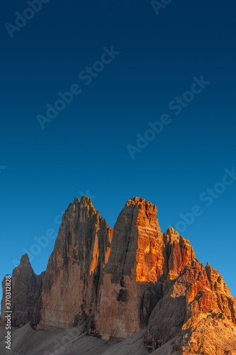 Beautiful sunset in magical Three Dolomite peaks at the national park Three Peaks (Tre Cime, Drei Zinnen) in Autumn colors at blue deep sky, South Tyrol, Italy, details