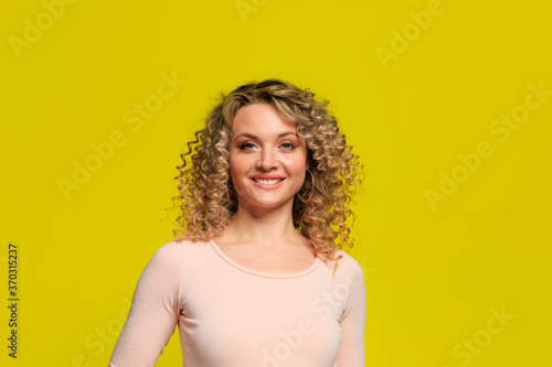 Smiling beautiful young woman posing on yellow background.