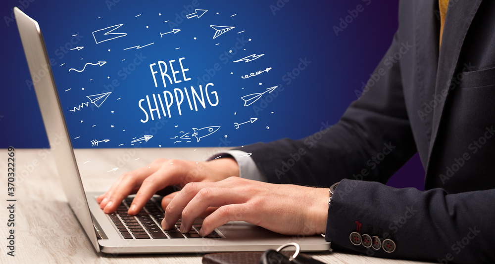 Businessman working on laptop with FREE SHIPPING inscription, online shopping concept Businessman working on laptop with FREE SHIPPING inscription, online shopping concept