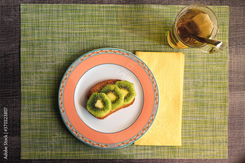 Desayuno saludable para dieta con una tostada con fruta y un te verde sobre un mantel