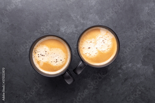 Two cups with coffee on dark stone background. Top view. Copy space
