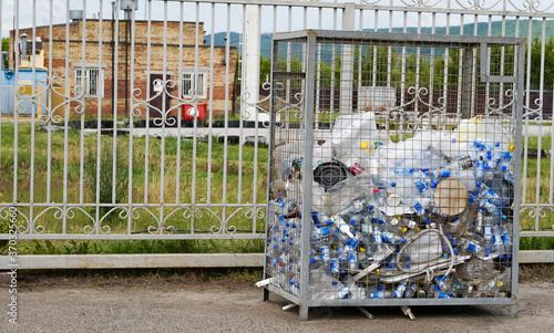 Almetyevsk, Russia - July 3, 2020:  Place for collecting sorted waste. Metal cage for collecting plastic bottles outside in the summer.