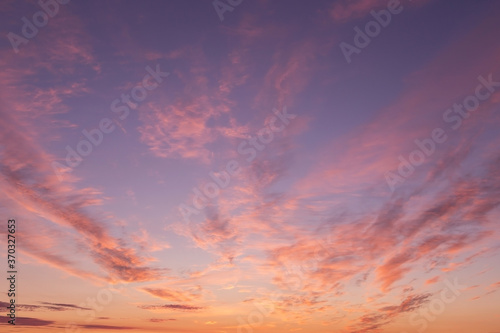 Dramatic soft sunrise, sunset. Beautiful pink violet orange clouds against blue sky background texture