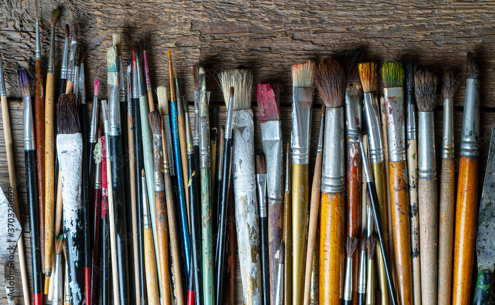 Fototapeta premium Mixed painting brushes lying on the wooden background.