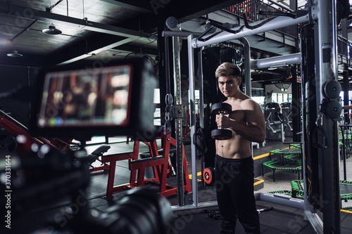 Sportman athlete doing exercise with dumbbells to camera while recording