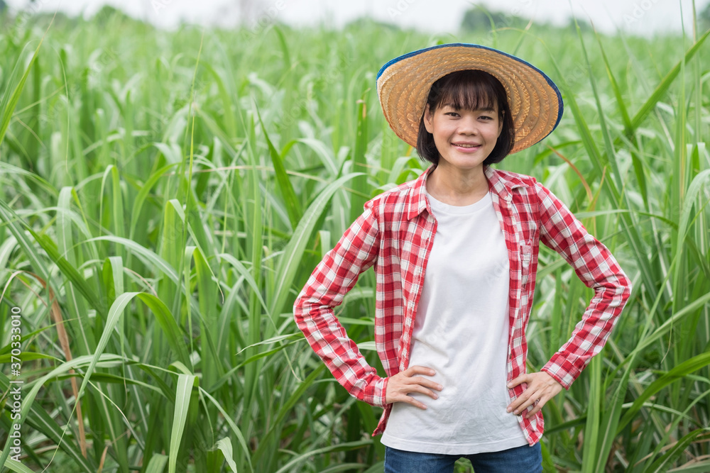 Asian farmer woman wear red shirt smile and standing at corn farm green leaf background