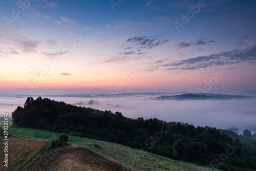 Fototapeta Naklejka Na Ścianę i Meble -  Beautiful Morning at Countryside. Rolling Hills in Morning Fog. Pink Sky. Blue Hour