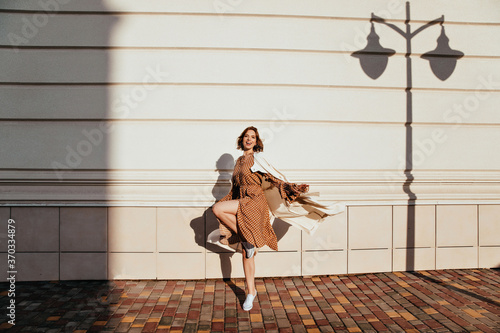Full-length portrait of active girl dancing in sunny day. Outdoor photo of debonair curly woman fooling around on the street.