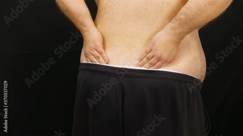 Man Rubs His Back in Pain Over Black Background