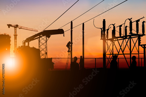 Silhouette electrician work installation of high voltage in high voltage stations safely and systematically over blurred natural background.