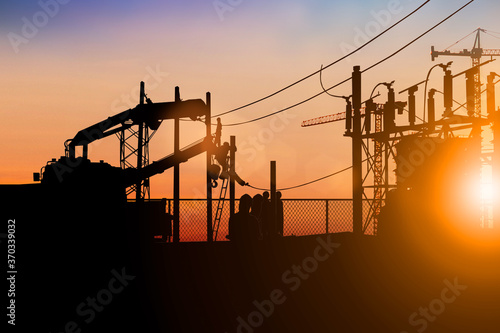 Fotografie Silhouette electrician work installation of high voltage in high voltage stations safely and systematically over blurred natural background