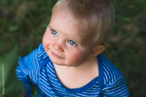 ittel baby sitting and looking up, nine month baby with blue eyes portrait, smiling face