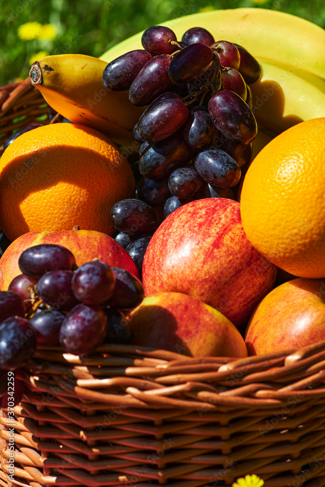Basket of various fruits in the sunlight on a meadow with yellow flowers. Basket of various fruits in the sunlight on a meadow with yellow flowers.