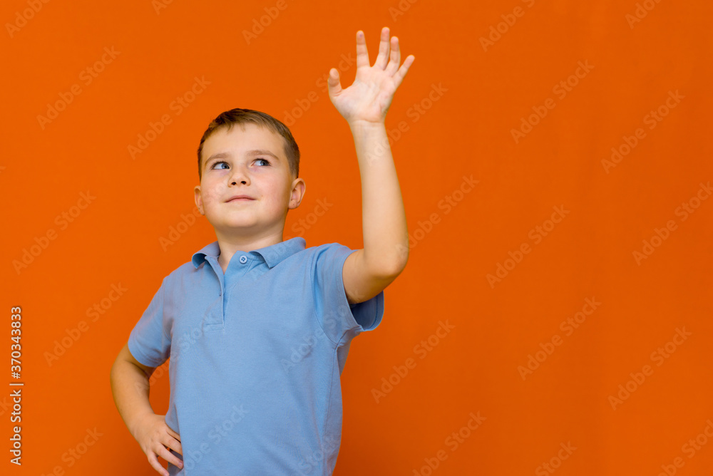 Portarait of caucasian happy smiling little boy with raised hand on orange wall Portarait of caucasian happy smiling little boy with raised hand on orange wall