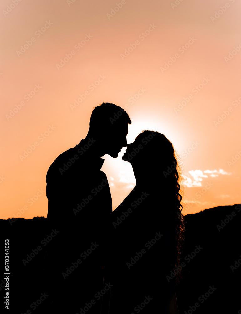 Lovely silhouette of a loving couple on a background of evening sky, sunset