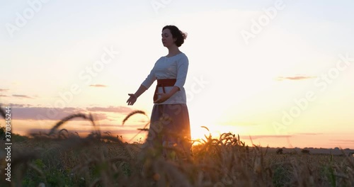 Female practicing qigong in summer fields with beautiful sunset on background 