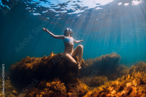Woman freediver sitting at rock underwater. Freediving in sea