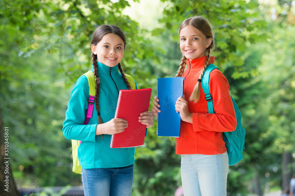 Fototapeta premium Schoolgirls with backpacks and textbooks in forest, exploring nature concept