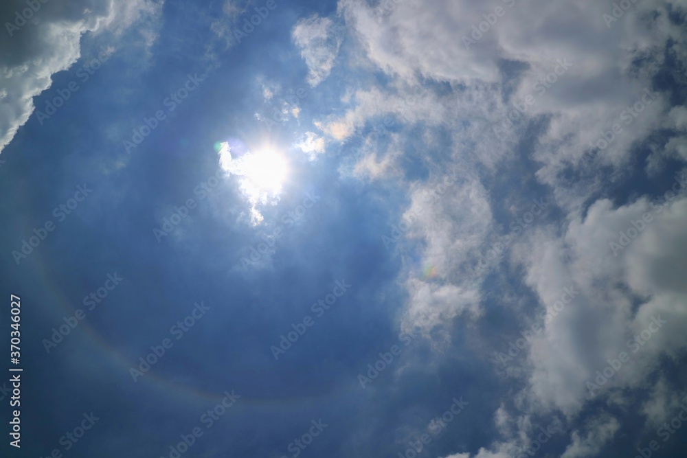 Fototapeta premium Beautiful sun halo with blue sky and big white cloud in summer time, soft focus. Nature background concept.