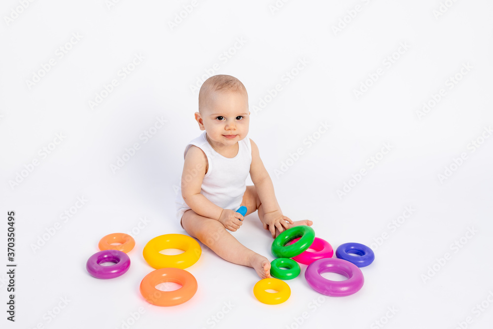 cute baby boy 8 months old playing with a pyramid on a white isolated background, place for text, early development of children cute baby boy 8 months old playing with a pyramid on a white isolated background, place for text, early development of children