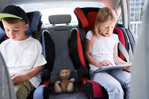 Cute siblings using gadgets while travelling by car