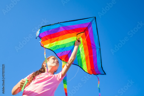girl holding a kite in her hands and looking at the sky