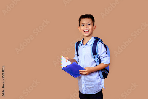 cheerful happy boy schoolboy with books in hands and backpack