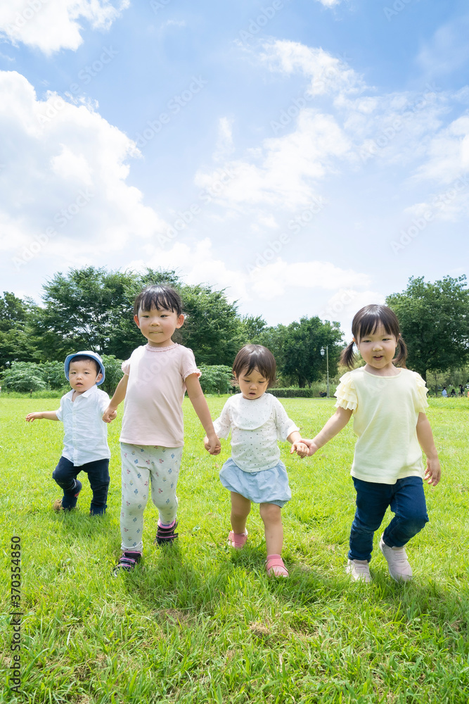 青空の下、手を繋いで元気に歩く子供たち