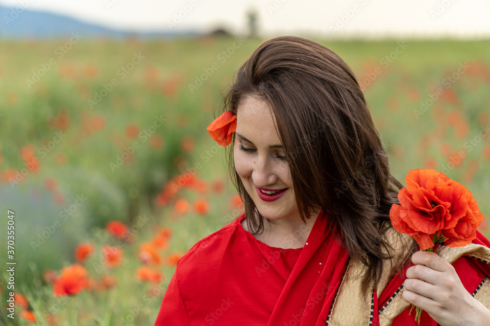 Naklejka premium Yound girl dressed in Indian Sari in a poppy flower garden