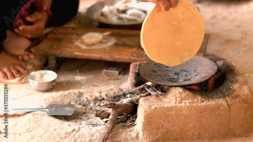 Female making Indian Bread ( rotis )on stove in Gujarat India, traditional indian food roti or Chapati, selective focus,Traditional way of making indian Roti or chapati in indian outdoor,