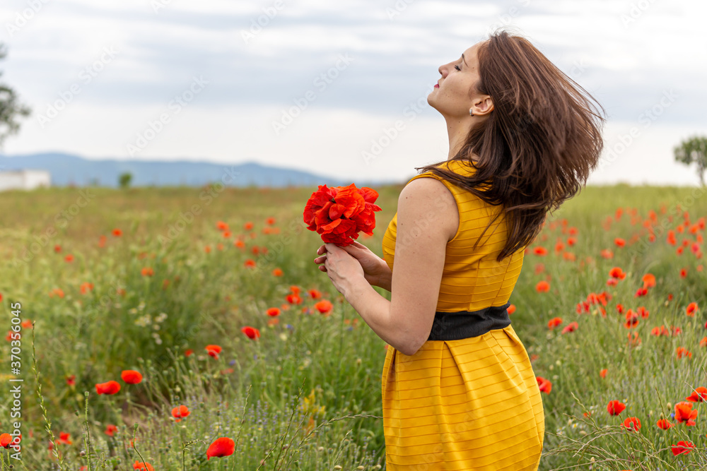 Girl dressed with yellow dress in a poppy garden Girl dressed with yellow dress in a poppy garden
