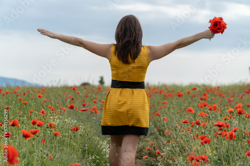 Fototapeta Naklejka Na Ścianę i Meble -  Girl dressed with yellow dress in a poppy garden