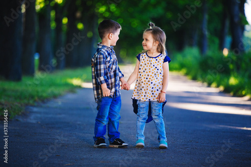 Children's love, a little boy and a girl, having fun, laugh and smile, and kiss outdoors