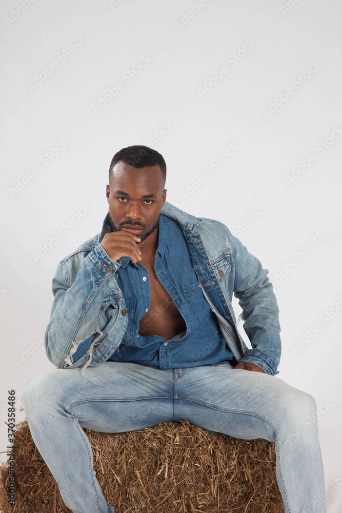 Thoughtful black man sitting on a bale of hay