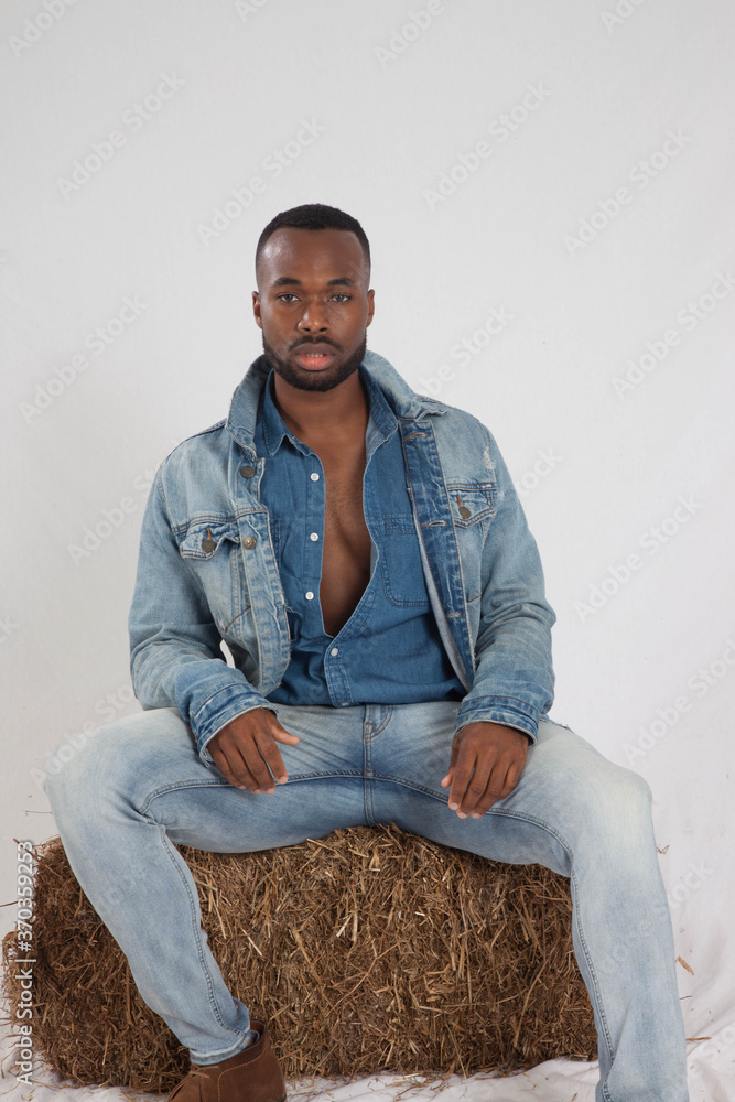 Thoughtful black man sitting on a bale of hay Thoughtful black man sitting on a bale of hay